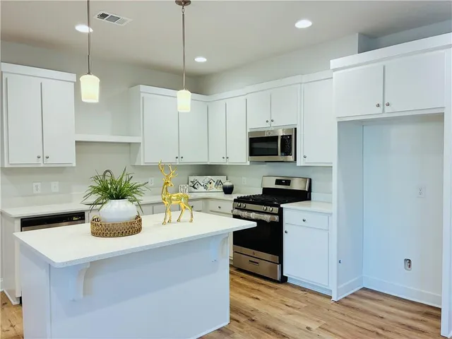 a kitchen with kitchen island white cabinets and stainless steel appliances