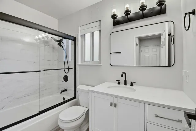 a bathroom with a toilet a sink a glass door a shower and a mirror