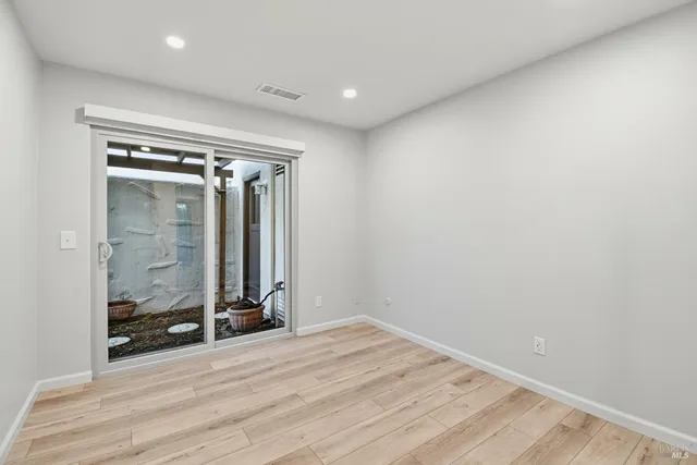 a view of a hallway with wooden floor and a bathroom