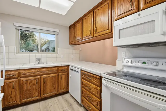 a kitchen with stainless steel appliances granite countertop a sink and cabinets with wooden floor