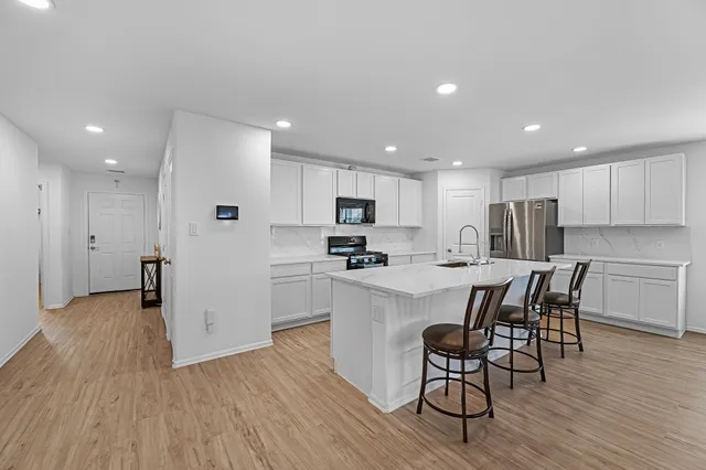 an open kitchen with wooden floor and stainless steel appliances