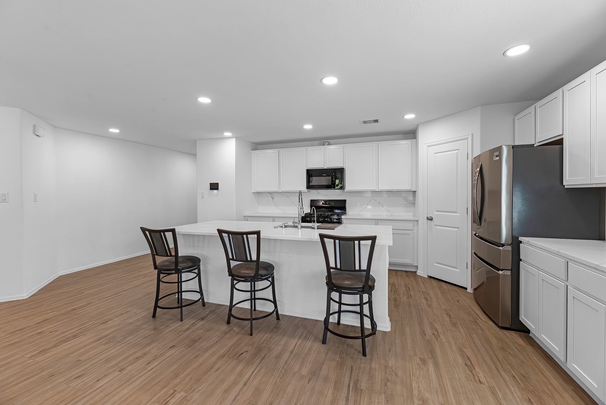 444 Maple Bend Lane La Marque, TX 77568 - Photo 8 of 32 a kitchen with stainless steel appliances a refrigerator a stove a sink dishwasher and a dining table with wooden floor