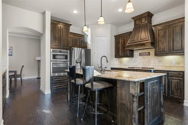 a kitchen with stainless steel appliances a dining table chairs and wooden floor