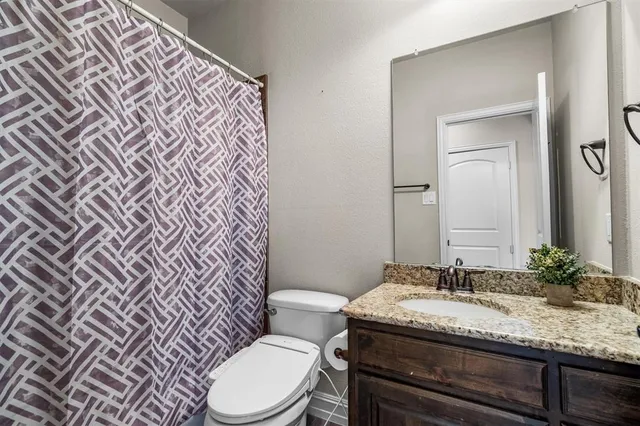 a bathroom with a granite countertop toilet sink and mirror
