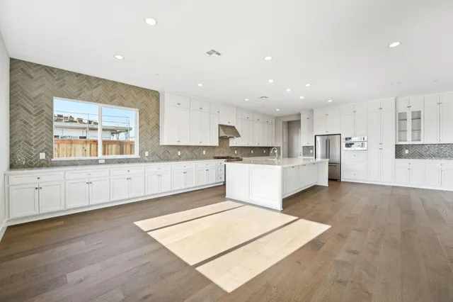 a large kitchen with stainless steel appliances kitchen island granite countertop a stove a sink and white cabinets