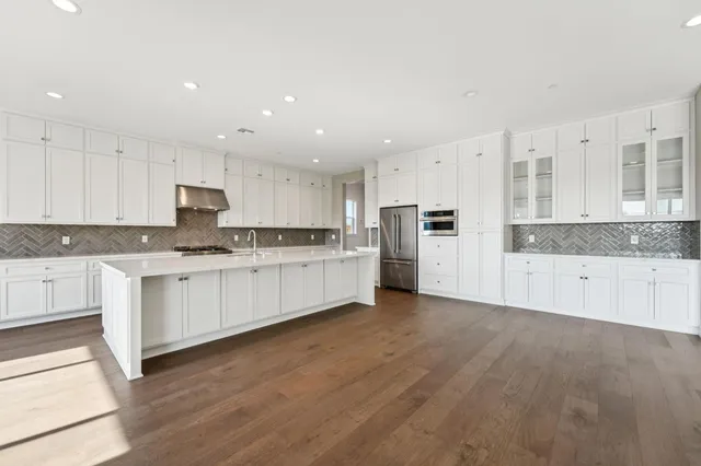 a large kitchen with cabinets wooden floor and stainless steel appliances