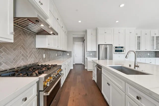 a kitchen with stainless steel appliances a sink stove and cabinets