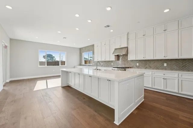 a large white kitchen with cabinets a sink a window and stainless steel appliances