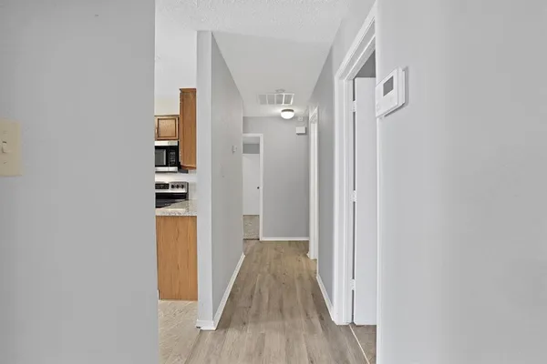 a view of a hallway with wooden floor and a bathroom