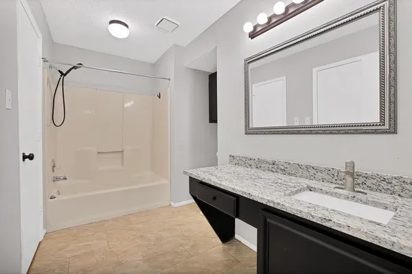a bathroom with a granite countertop sink a mirror and a bathtub