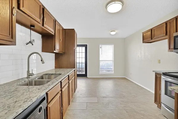 a kitchen with granite countertop a sink a stove and cabinets