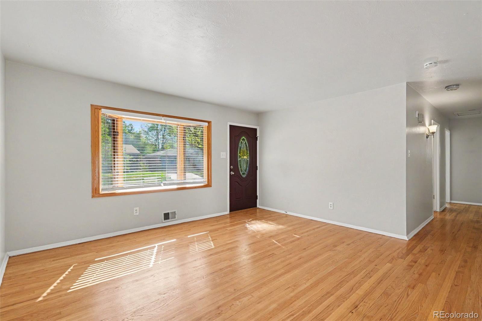 3217 South Stuart Street Denver, CO 80236 - Photo 6 of 29 a view of an empty room with wooden floor and a window