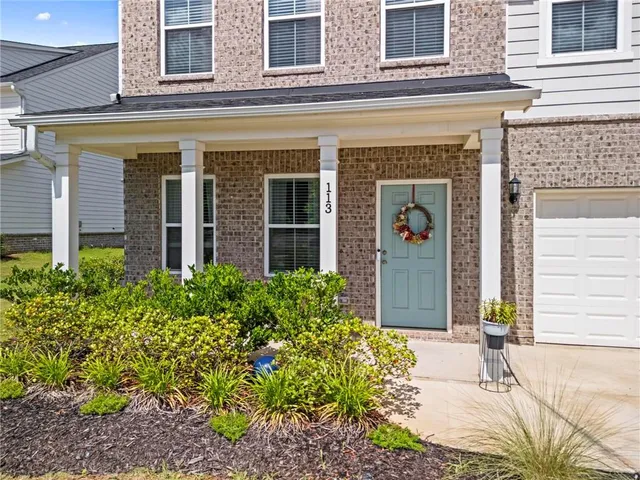 front view of a brick house with potted plants