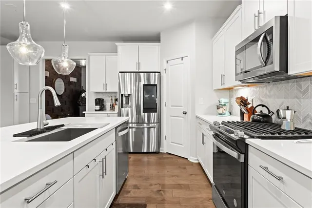 a kitchen with stainless steel appliances granite countertop a stove a refrigerator and a sink