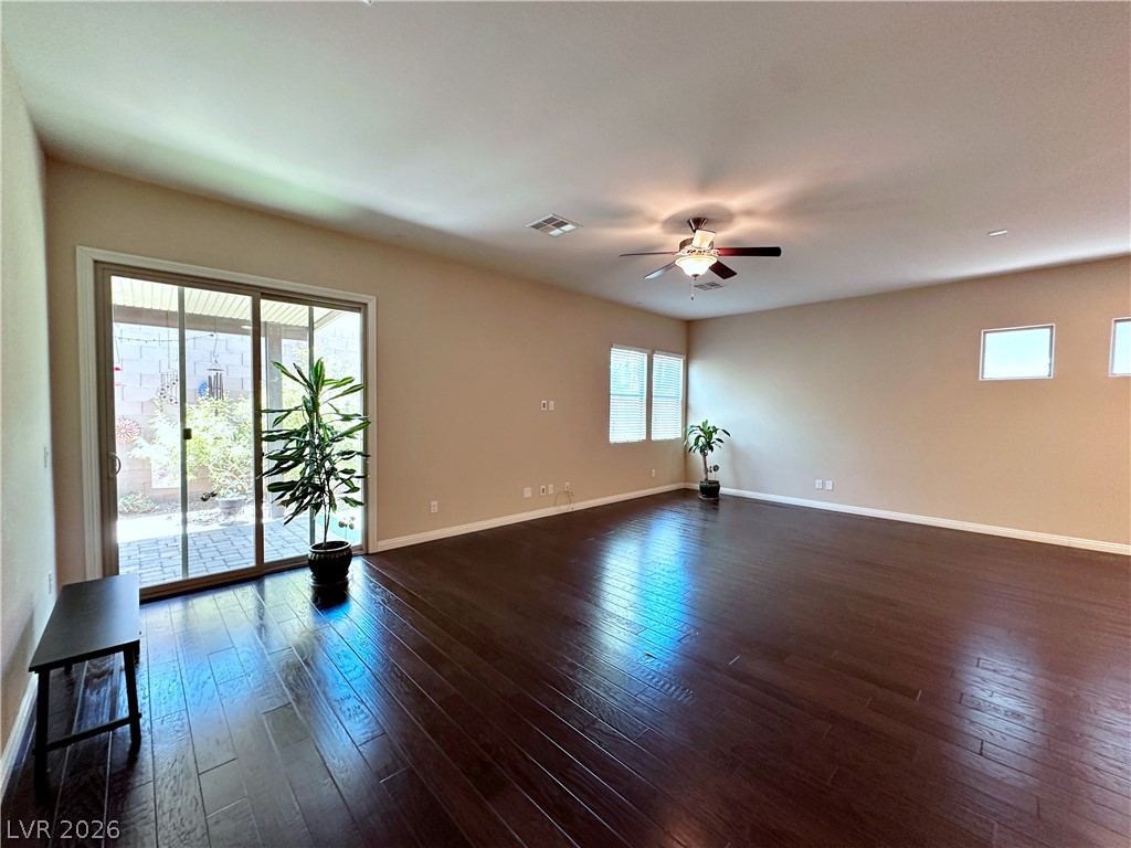 71 Newton Ridge Way Las Vegas, NV 89183 - Photo 9 of 40 Rich hardwood flooring complements a spacious room featuring a sliding glass door and multiple windows.