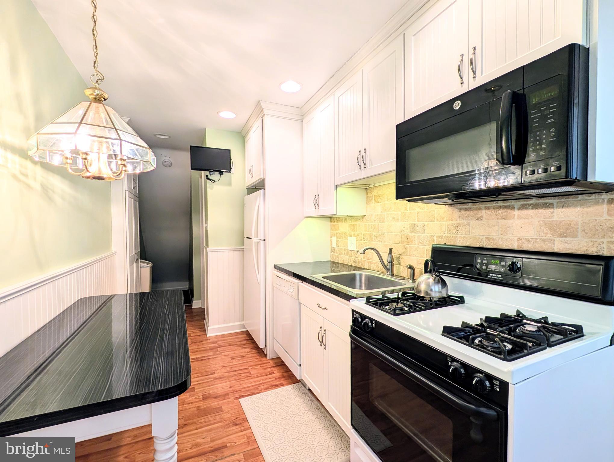 1439 Michigan Avenue Swarthmore, PA 19081 - Photo 37 of 54 a kitchen with stainless steel appliances a stove a microwave a refrigerator and cabinets