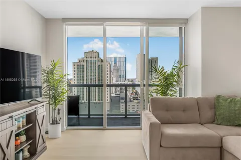 a living room with furniture a flat screen tv and a floor to ceiling window