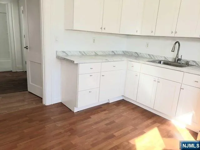 a kitchen with granite countertop white cabinets and sink