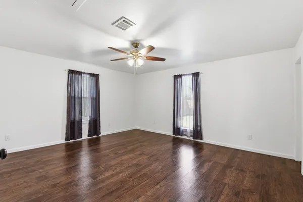 an empty room with wooden floor and ceiling fan