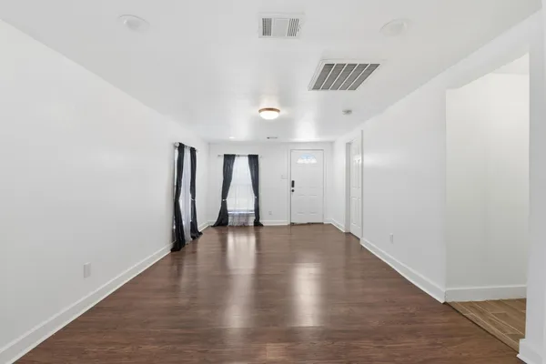 a view of an empty room with wooden floor