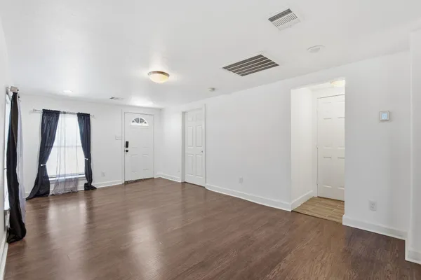 an empty room with wooden floor and a ceiling fan