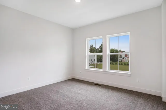 a view of a white house with a yard and table and chairs under an umbrella