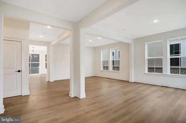 a view of an empty room with wooden floor and windows