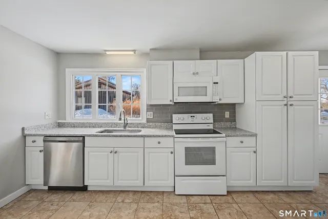 a kitchen with stainless steel appliances granite countertop a stove a sink and a refrigerator