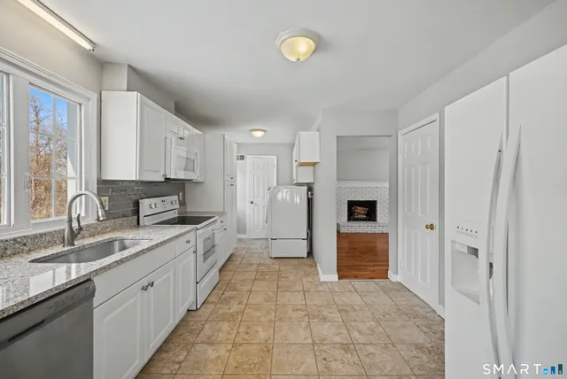 a large white kitchen with a sink and stainless steel appliances