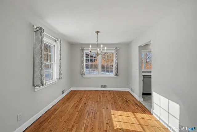 a view of an empty room with window and wooden floor