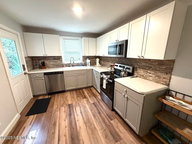 a kitchen with stainless steel appliances granite countertop a refrigerator a stove a sink and a microwave