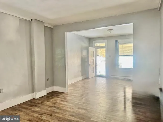 a view of an empty room with wooden floor and a window