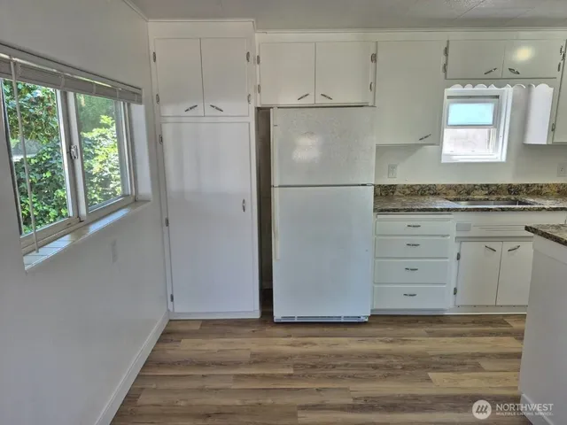 a view of a kitchen with white cabinets and wooden floor