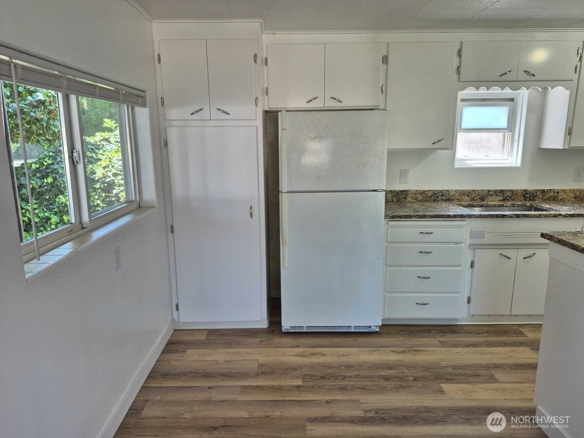 317 7th Street Southwest, Unit 6 Puyallup, WA 98371 - Photo 4 of 8 a view of a kitchen with white cabinets and wooden floor