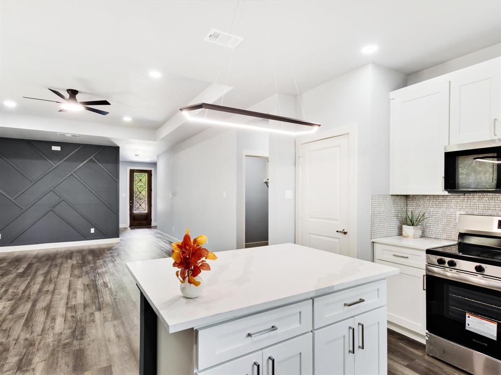 4705 Point La Vista Road Malakoff, TX 75148 - Photo 25 of 40 Open-concept kitchen featuring an island with a light-toned countertop, white cabinetry with dark hardware, and a tile backsplash
