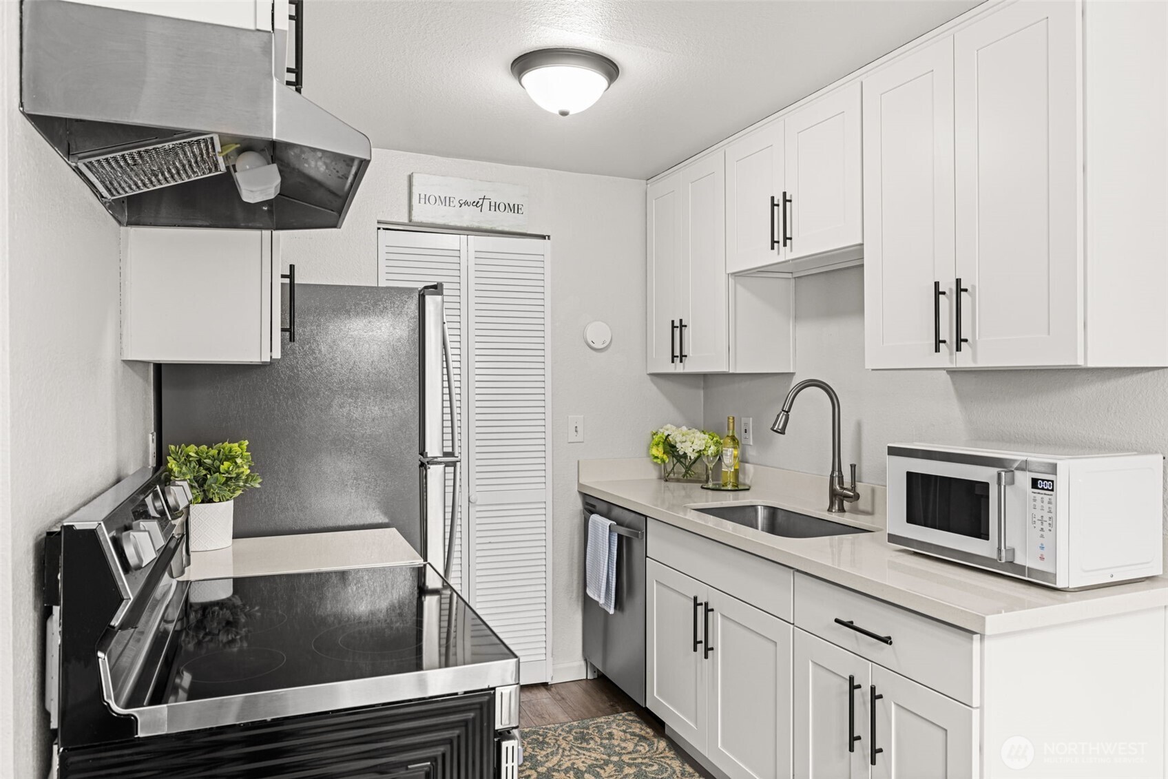 15210 Macadam Road South, Unit D211 Tukwila, WA 98188 - Photo 6 of 26 a kitchen with stainless steel appliances granite countertop a sink a stove and a refrigerator