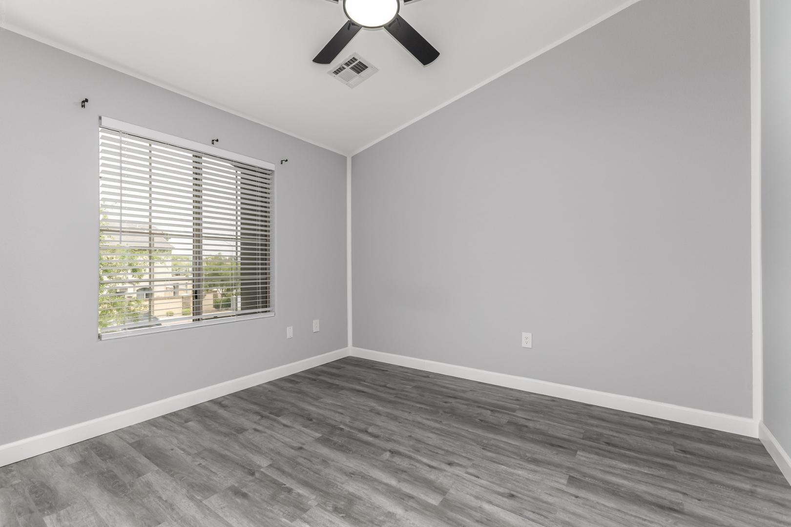 1350 South Greenfield Road, Unit 2205 Mesa, AZ 85206 - Photo 21 of 42 a view of an empty room with wooden floor and a window