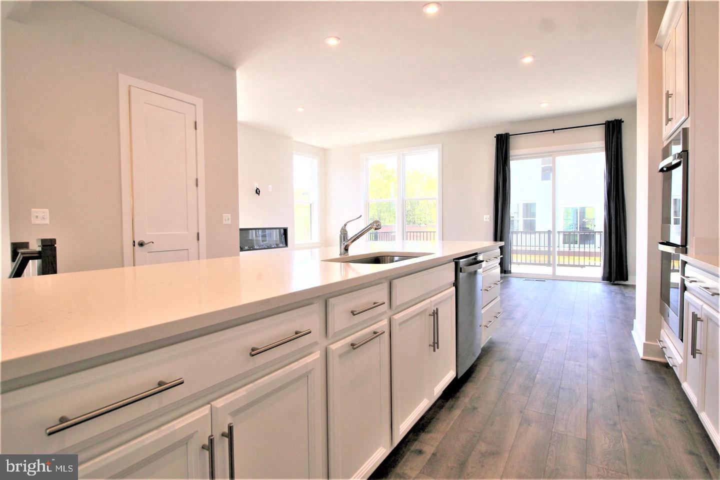 2471 Liberty Loop Herndon, VA 20171 - Photo 13 of 35 a open white kitchen with center island and a wooden floor