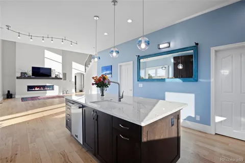 a kitchen with a center island wooden floor appliances and a view of living room