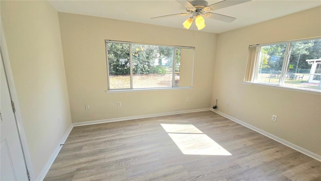 11239 Southwest 77th Court Ocala, FL 34476 - Photo 8 of 22 an empty room with wooden floor fan and windows
