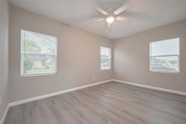 a view of an empty room with a window and wooden floor