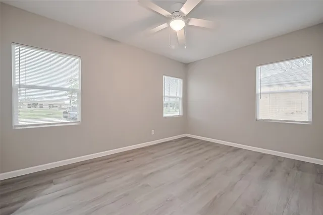 a view of an empty room with a window and wooden floor