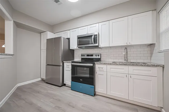 a kitchen with white cabinets and stainless steel appliances