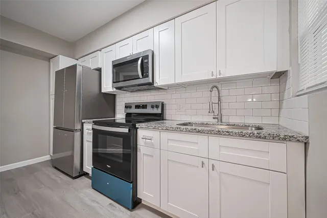 a kitchen with granite countertop white cabinets and stainless steel appliances