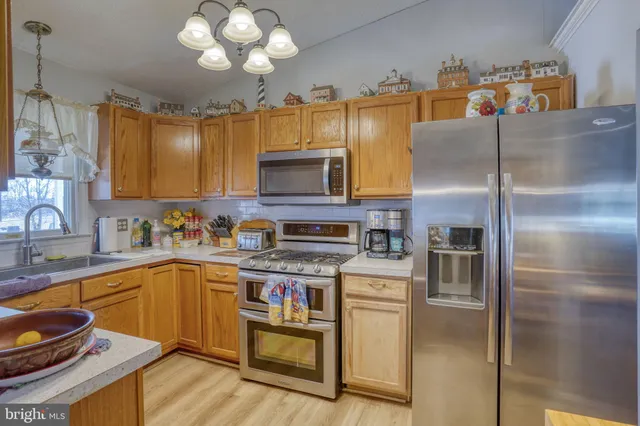 a kitchen with stainless steel appliances granite countertop a refrigerator a sink dishwasher a stove with wooden cabinets and floor