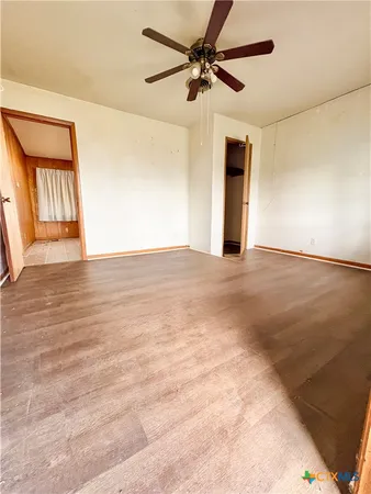 an empty room with windows and fan
