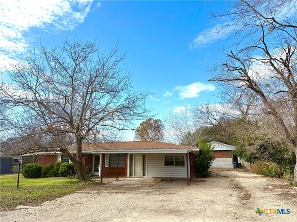 a front view of a house with a garden and trees