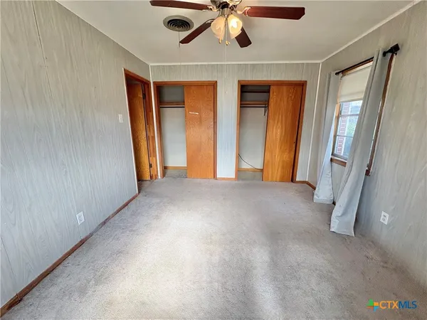 a view of empty room with a ceiling fan and window