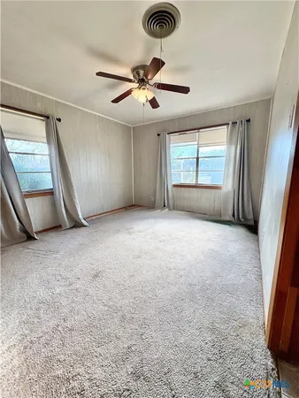an empty room with windows and fan
