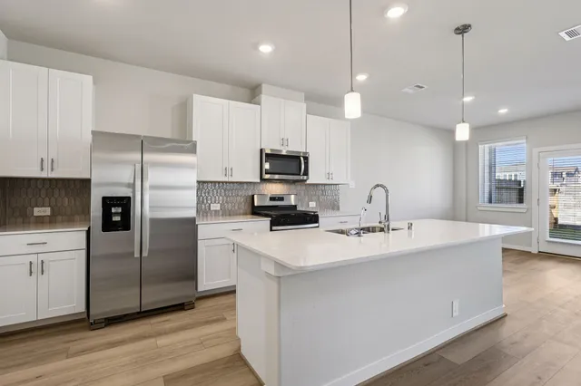 a kitchen with kitchen island a counter space a sink appliances and cabinets